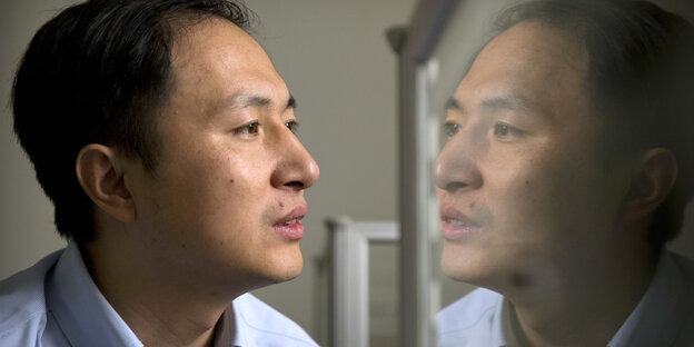 He Jiankui spiegelt sich in einer Glasscheibe wider