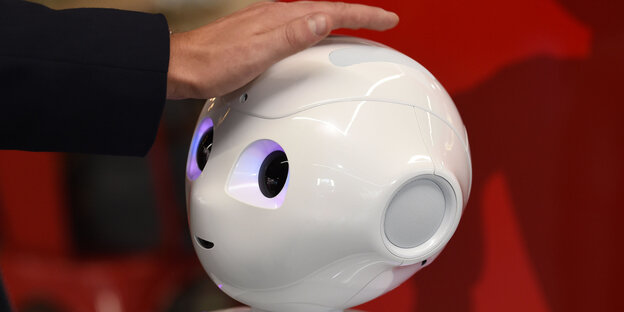 Ein Roboterkopf wird gestreichelt Ein Roboterkopf wird gestreichelt
