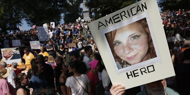 Ein Foto von Heather Heyer mit der Beschriftung „American hero“ wir bei einer Demonstration in die Höhe gehalten Ein Foto von Heather Heyer mit der Beschriftung „American hero“ wir bei einer Demonstration in die Höhe gehalten