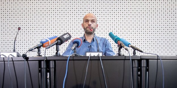 Marco Bülow an einem Tisch hinter Mikros Marco Bülow an einem Tisch hinter Mikros
