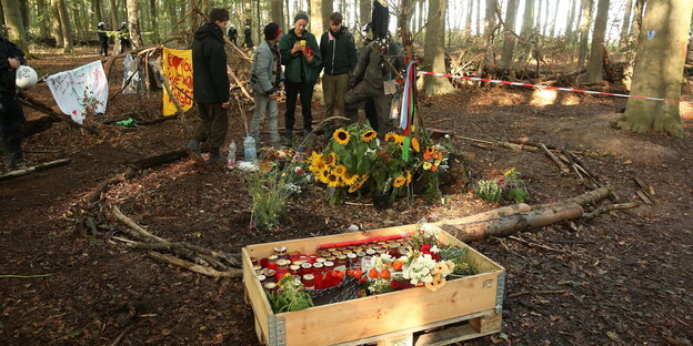 AktivistInnen räumen Blumen und Kerzen für den im Hambacher Wald abgestürzten Journalisten Steffen Meyn in eine Kiste AktivistInnen räumen Blumen und Kerzen für den im Hambacher Wald abgestürzten Journalisten Steffen Meyn in eine Kiste