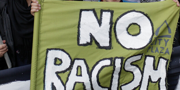 Ein Junge hält ein Transparent mit der Aufschrift "No Racism" hoch Ein Junge hält ein Transparent mit der Aufschrift "No Racism" hoch