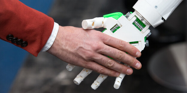Ein humanoider Roboter gibt einem Menschen die Hand am Stand von ioX Lab bei der IT-Messe CeBIT Ein humanoider Roboter gibt einem Menschen die Hand am Stand von ioX Lab bei der IT-Messe CeBIT