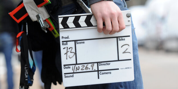 Eine Person trägt eine Filmklappe Eine Person trägt eine Filmklappe