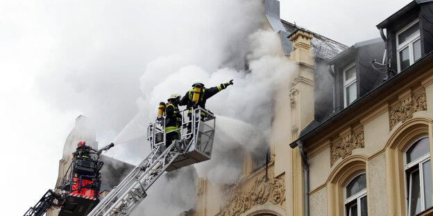 Feuermann auf Leiter vor qualmendem Haus Feuermann auf Leiter vor qualmendem Haus