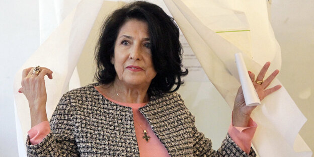 Eine Frau mit dunklen Haaren kommt aus einer Wahlkabine Eine Frau mit dunklen Haaren kommt aus einer Wahlkabine