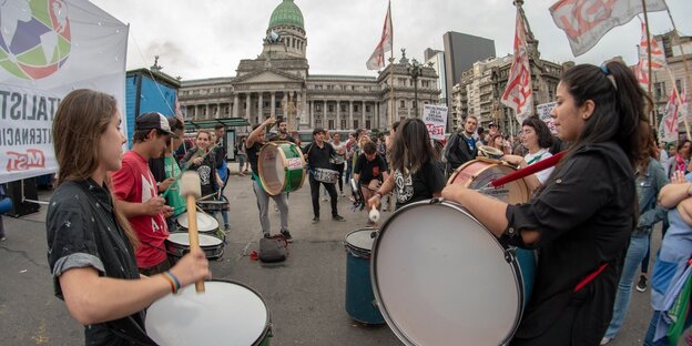 Vor dem Gebäude des argentinischen Kongresses stehen junge Menschen mit Trommeln