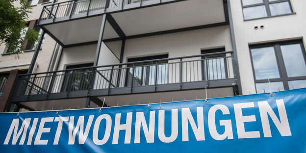 Ein Transparent mit der Aufschrift "Mietwohnungen" hängt an einem haus