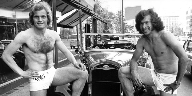 Uli Hoeneß und Paul Breitner nur mit Shorts bekleidet posieren vor einem Oldtimer Uli Hoeneß und Paul Breitner nur mit Shorts bekleidet posieren vor einem Oldtimer