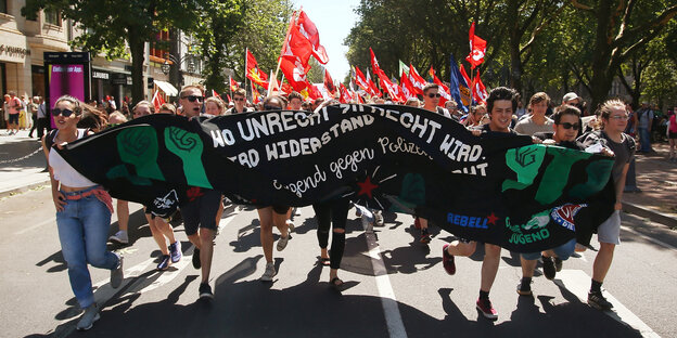 Demonstranten rennen mit einem Banner gegen das geplante neue Polizeigesetz durch die Düsseldorfer Königsallee. Demonstranten rennen mit einem Banner gegen das geplante neue Polizeigesetz durch die Düsseldorfer Königsallee.