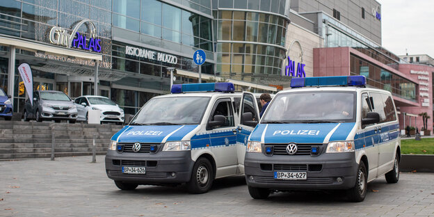 Zwei Polizeifahrzeuge vor einer Shopping-Mall Zwei Polizeifahrzeuge vor einer Shopping-Mall