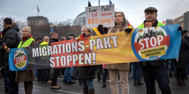 Menschen protestieren mit Plakaten gegen den UN-Migrationspakt Menschen protestieren mit Plakaten gegen den UN-Migrationspakt