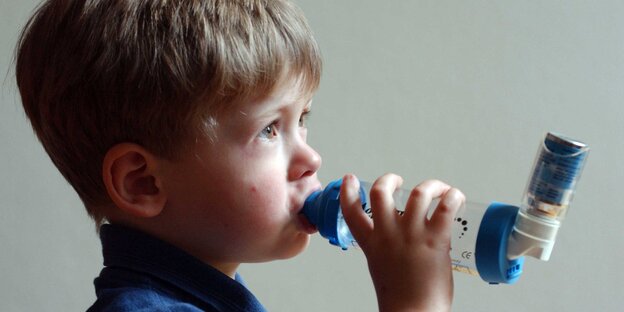 Ein Kind atmet durch ein Asthma-Gerät Ein Kind atmet durch ein Asthma-Gerät