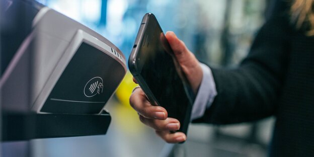 So kann Apple Pay aussehen: Eine Person hält ein Smartphone vor ein Bezahlterminal So kann Apple Pay aussehen: Eine Person hält ein Smartphone vor ein Bezahlterminal