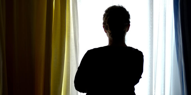 Eine junge Frau steht im Zimmer eines Frauenhauses Eine junge Frau steht im Zimmer eines Frauenhauses