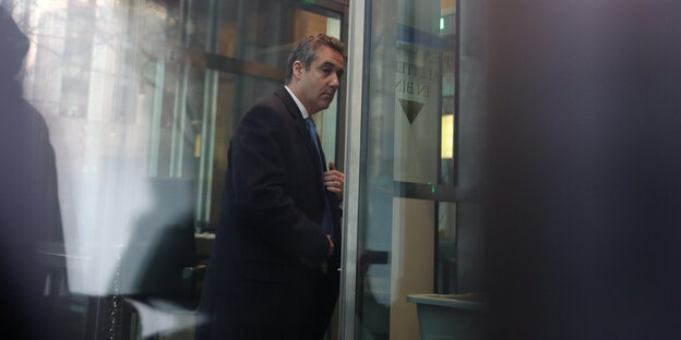 Ein Mann im schwarzen Mantel tritt aus einer Tür Ein Mann im schwarzen Mantel tritt aus einer Tür