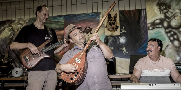 Ozan Ata Canani spielt stehend auf der Bühne seine Saz Ozan Ata Canani spielt stehend auf der Bühne seine Saz