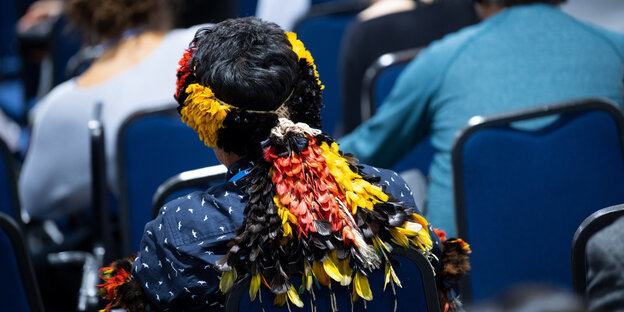 Ein Vertreter eines indigenen Volkes verfolgt eine Pressekonferenz zum Thema "Indigene Völker" beim Weltklimagipfel Ein Vertreter eines indigenen Volkes verfolgt eine Pressekonferenz zum Thema "Indigene Völker" beim Weltklimagipfel
