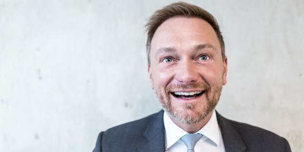 Christian Lindner, ein Mann in Anzug und Krawatte, lacht vor einer weißen Wand Christian Lindner, ein Mann in Anzug und Krawatte, lacht vor einer weißen Wand
