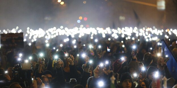 Viele Menschen halten im Dunkeln ihr Smartphone hoch, um Licht zu machen. Viele Menschen halten im Dunkeln ihr Smartphone hoch, um Licht zu machen.