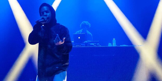 Rapper Earl Sweatshirt mit Mikrofon auf einer Bühne Rapper Earl Sweatshirt mit Mikrofon auf einer Bühne