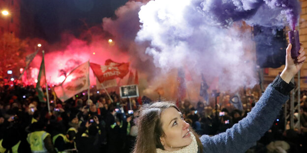 Frau hält auf einer Demonstration eine Rauchfackel