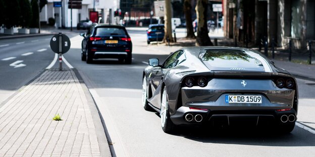 Ein anthrazitfarbener Ferrari fährt auf einer Straße Ein anthrazitfarbener Ferrari fährt auf einer Straße