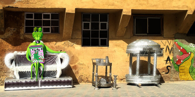 Silberne Möbel und ein Plastikkrokodil stehen vor einem Haus Silberne Möbel und ein Plastikkrokodil stehen vor einem Haus