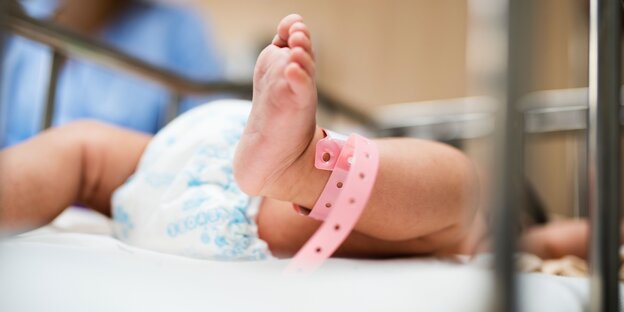 Ein Neugeborenes mit einem Krankenhaus-Bändchen um den Fuß Ein Neugeborenes mit einem Krankenhaus-Bändchen um den Fuß