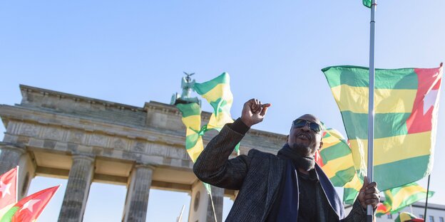 Ein Mann mit der Fahne Togos vor dem Brandenburger Tor Ein Mann mit der Fahne Togos vor dem Brandenburger Tor