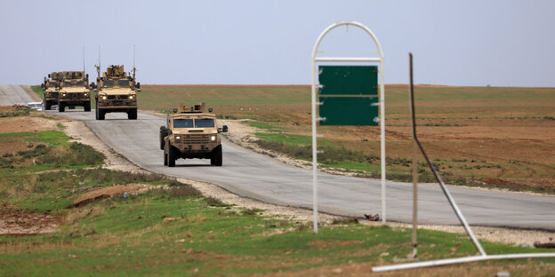 Militärfahrzeuge auf einer Straße durch unbebautes Land Militärfahrzeuge auf einer Straße durch unbebautes Land