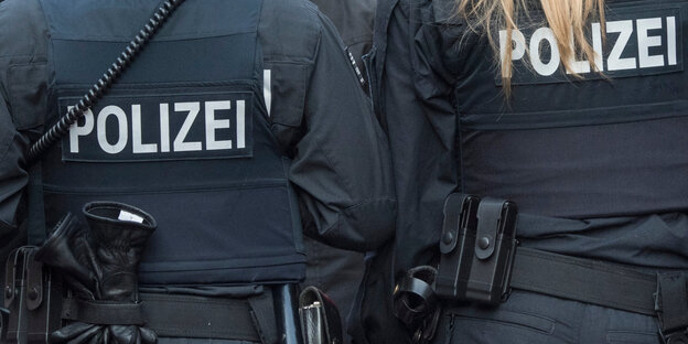Die Rücken zweier Polizisten in Uniform Die Rücken zweier Polizisten in Uniform