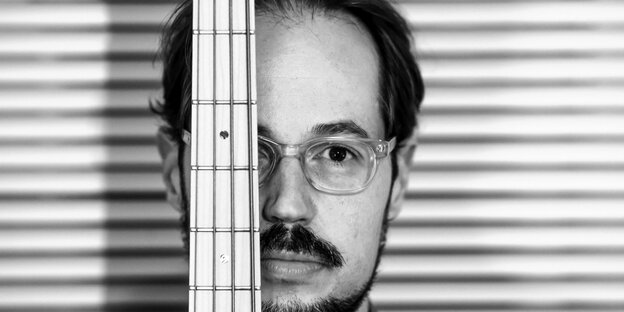 Ein Man hält den Hals seiner Bassgitarre vors Gesicht Ein Man hält den Hals seiner Bassgitarre vors Gesicht