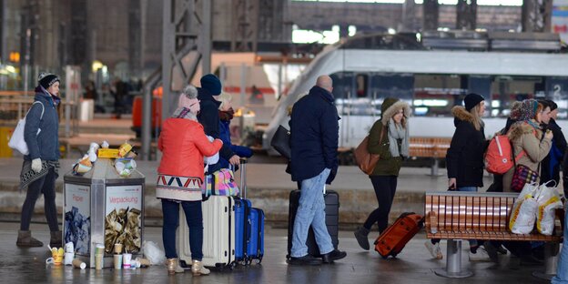 Reisende in Winterkleidung stehen auf einem Bahnsteig Reisende in Winterkleidung stehen auf einem Bahnsteig