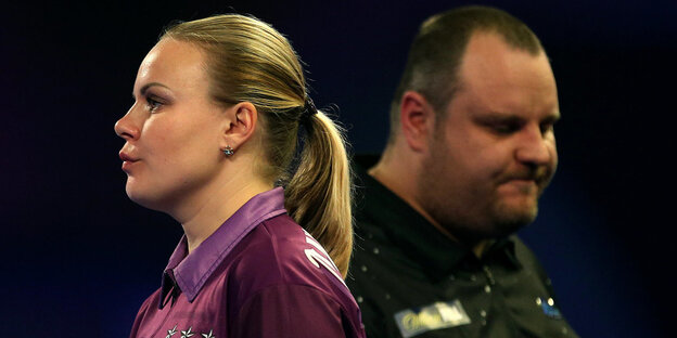 Anastassija Dobromyslowa hat Dartspfeile in der Hand, hinter ihr steht Ryan Joyce Anastassija Dobromyslowa hat Dartspfeile in der Hand, hinter ihr steht Ryan Joyce