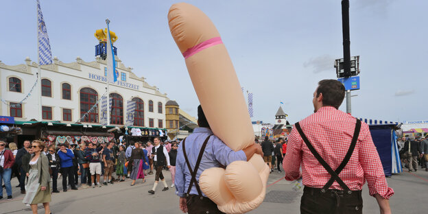 Zwei männliche Oktoberfest-Besucher laufen mit einen aufgeblasenen Penis-Figur über das Gelände Zwei männliche Oktoberfest-Besucher laufen mit einen aufgeblasenen Penis-Figur über das Gelände