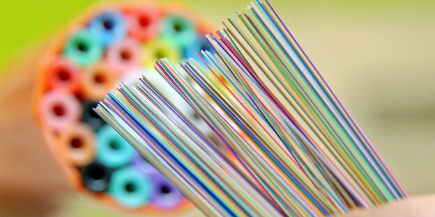 Ein buntes Kabelbündel aus einem Glasfaserkabel vor einer sogenannten Speedpipe für ein Glasfasernetzwerk Ein buntes Kabelbündel aus einem Glasfaserkabel vor einer sogenannten Speedpipe für ein Glasfasernetzwerk
