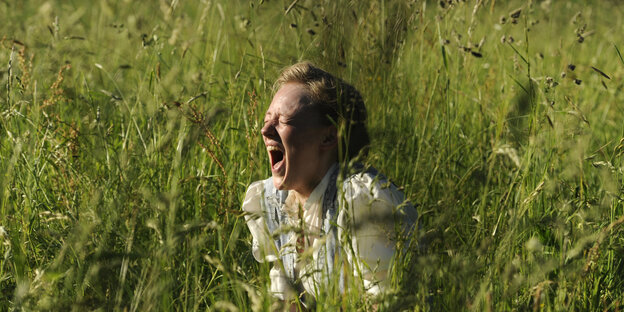 Szene aus dem Film: Eine junge Frau sitzt im Gras und schreit. Szene aus dem Film: Eine junge Frau sitzt im Gras und schreit.