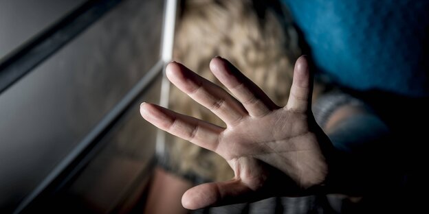Eine Person versucht sich hinter einer ausgestreckten Hand zu verstecken Eine Person versucht sich hinter einer ausgestreckten Hand zu verstecken