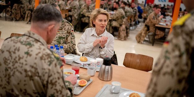 Ursula von der Leyen sitzt zwischen Soldaten