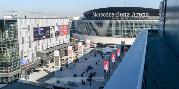 Das Bild zeigt die Mercedes Benz Arena hinter dem neuen Mercedes Platz in Berlin-Friedrichshain, graue Gebäude aus Glas und Beton. Das Bild zeigt die Mercedes Benz Arena hinter dem neuen Mercedes Platz in Berlin-Friedrichshain, graue Gebäude aus Glas und Beton.