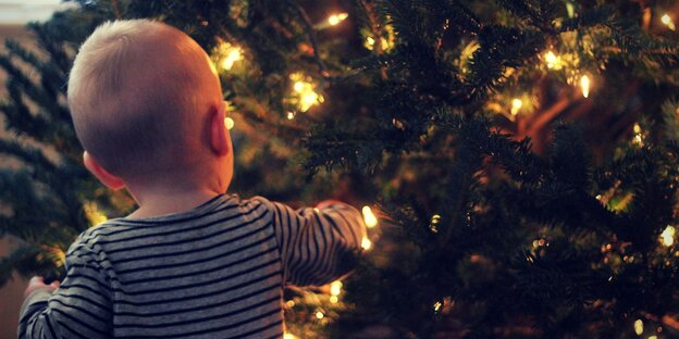 Ein kleiner Junge vor dem Tannenbaum