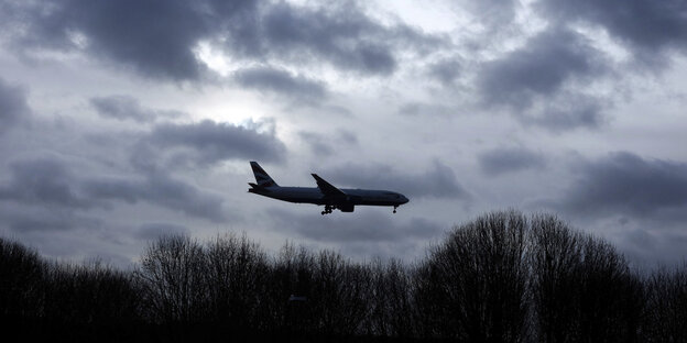 Ein Flugzeug fliegt über bewölkten, dunklen Himmel