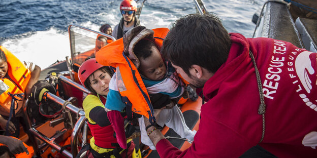 Ein Baby wird in das Rettungsboot der spanischen NGO Proactiva Open Arms gehoben Ein Baby wird in das Rettungsboot der spanischen NGO Proactiva Open Arms gehoben