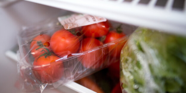 In Plastik verpackte Tomaten und Salatherzen liegen in einem Kühlschrank. In Plastik verpackte Tomaten und Salatherzen liegen in einem Kühlschrank.