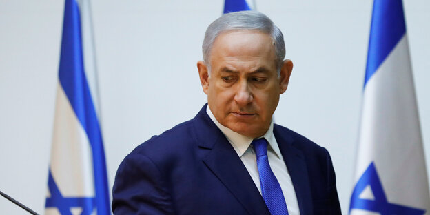 Israels Ministerpräsident Benjamin Netanjahu steht vor israelischen Fahnen Israels Ministerpräsident Benjamin Netanjahu steht vor israelischen Fahnen