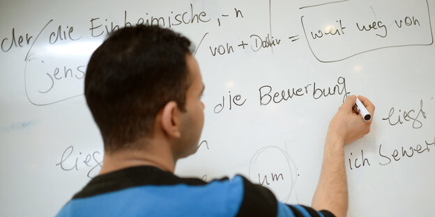 Ein junger Mann übt an einer Tafel das Schreiben in deutscher Sprache. Ein junger Mann übt an einer Tafel das Schreiben in deutscher Sprache.
