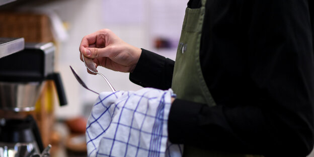 Ein Mann trocknet Besteck ab Ein Mann trocknet Besteck ab