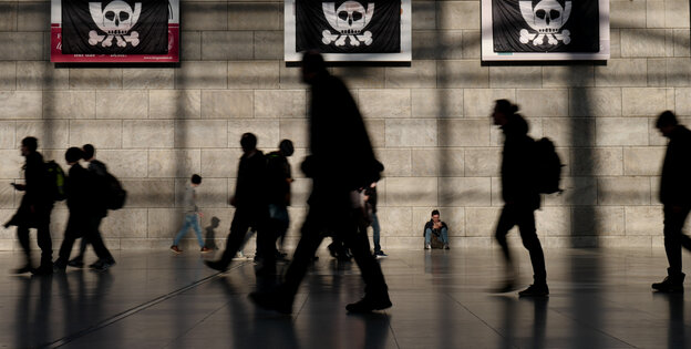 Die Silhouetten von laufenden Menschen in einer Messehalle