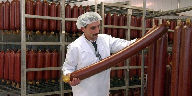 Ein Mitarbeiter des Bremer Wurstherstellers Könecke hält im Werk im polnischen Slubice eine große Salami in seinen Händen. Ein Mitarbeiter des Bremer Wurstherstellers Könecke hält im Werk im polnischen Slubice eine große Salami in seinen Händen.